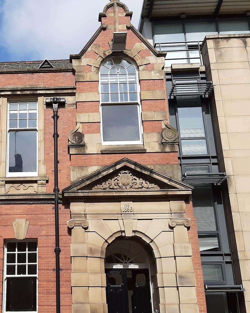 The red-brick front of 14 Byrom Street, with its arched window, carved 1896 datestone and arched doorway